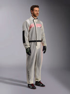 Alpinestars Kart Rain Suit, sobretraje de karting impermeable y transparente, material semitransparente que muestra un mono de carreras rosa y blanco debajo, con cremallera asimétrica negra, parche reforzado en el codo y banda negra en la cintura, usado con guantes de karting negros y calzado de competición