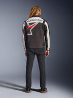 Alpinestars Axton Jacket, Motorcycle Jacket, Black Off White and Bright Red, back view on a model, featuring a large Alpinestars star logo on the back, off-white sleeve panels, worn with black pants, vintage-inspired racing teamwear design