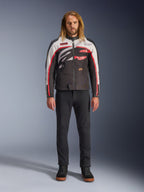 Alpinestars Axton Jacket, Motorcycle Jacket, Black Off White and Bright Red, worn by a model with black pants and sneakers, featuring a bold wrap-around logo and vintage racing-inspired design
