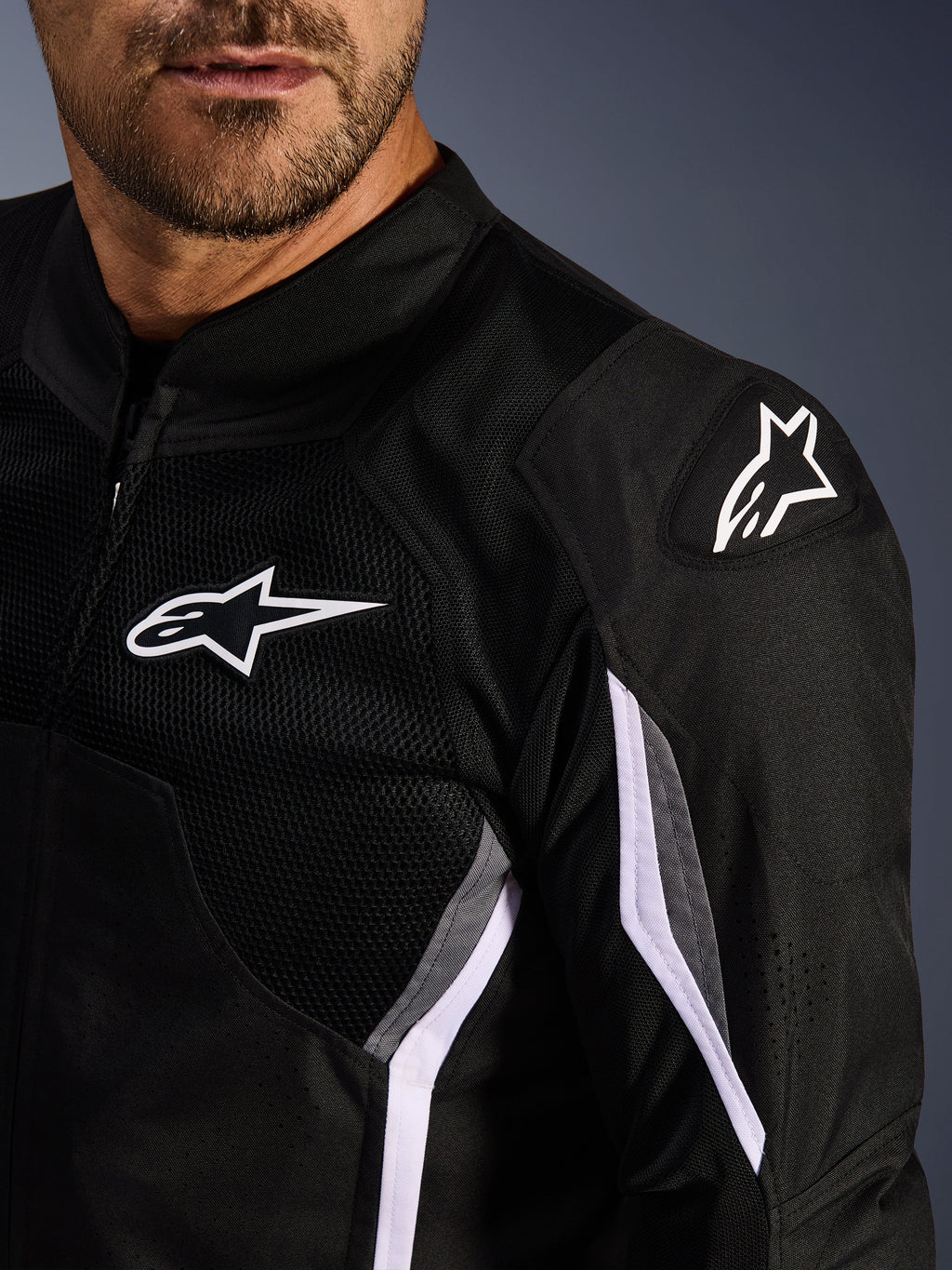 Chaqueta Alpinestars AST V3 Air, chaqueta textil de motociclismo, negro, gris oscuro y blanco, primer plano con paneles de malla, logotipo blanco de Alpinestars en el pecho y el hombro, y deslizadores de hombro externos DFS GP Lite Evo