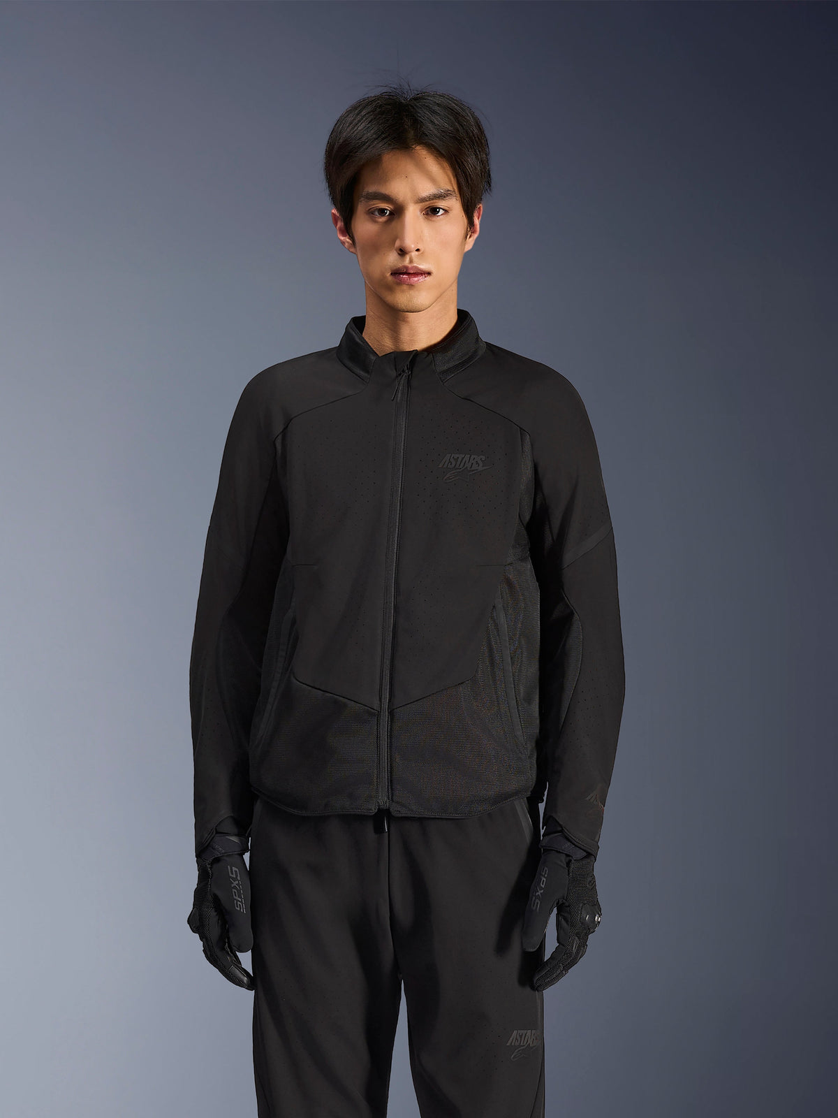Alpinestars Aeroshell Airflow Jacket in Black Anthracite, lightweight motorcycle jacket with laser-perforated ventilation on the chest and sleeves, breathable mesh panels, and a sleek sport-cut design, worn by a model with black riding gloves.