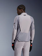 Chaqueta Alpinestars Aeroshell Airflow en Mid Gray Anthracite, vista trasera que muestra paneles de malla transpirable y perforaciones láser, construcción técnica de softshell elástico con un panel trasero alargado, combinada con pantalones grises a juego y guantes negros para un look deportivo.
