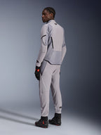 Chaqueta Alpinestars Aeroshell Airflow en color Mid Gray Anthracite, combinada con pantalones a juego y guantes de carreras negros, vista trasera que muestra los paneles perforados por láser y el ajuste deportivo, equipamiento profesional para motociclismo