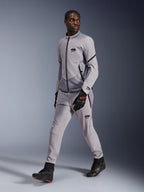 Chaqueta Alpinestars Aeroshell Airflow en color Mid Gray Anthracite, lucida por un modelo masculino con pantalones de pilotaje grises a juego y guantes negros, con ventilación en el pecho perforada por láser y un elegante diseño de corte deportivo.
