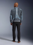 Alpinestars Flight Air Jacket en Storm Gray, vista trasera de un modelo masculino vistiendo una chaqueta de moto de estilo urbano con paneles de malla 3D y la marca Alpinestars en vertical, combinada con pantalones negros para un look urbano moderno