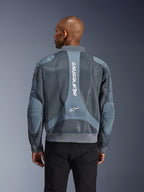 Chaqueta Alpinestars Flight Air en color Storm Gray, vista trasera en un modelo, chaqueta de moto urbana con paneles de malla 3D extendidos, marca Alpinestars vertical en la espalda y cuello y dobladillo acanalados estilo bomber.