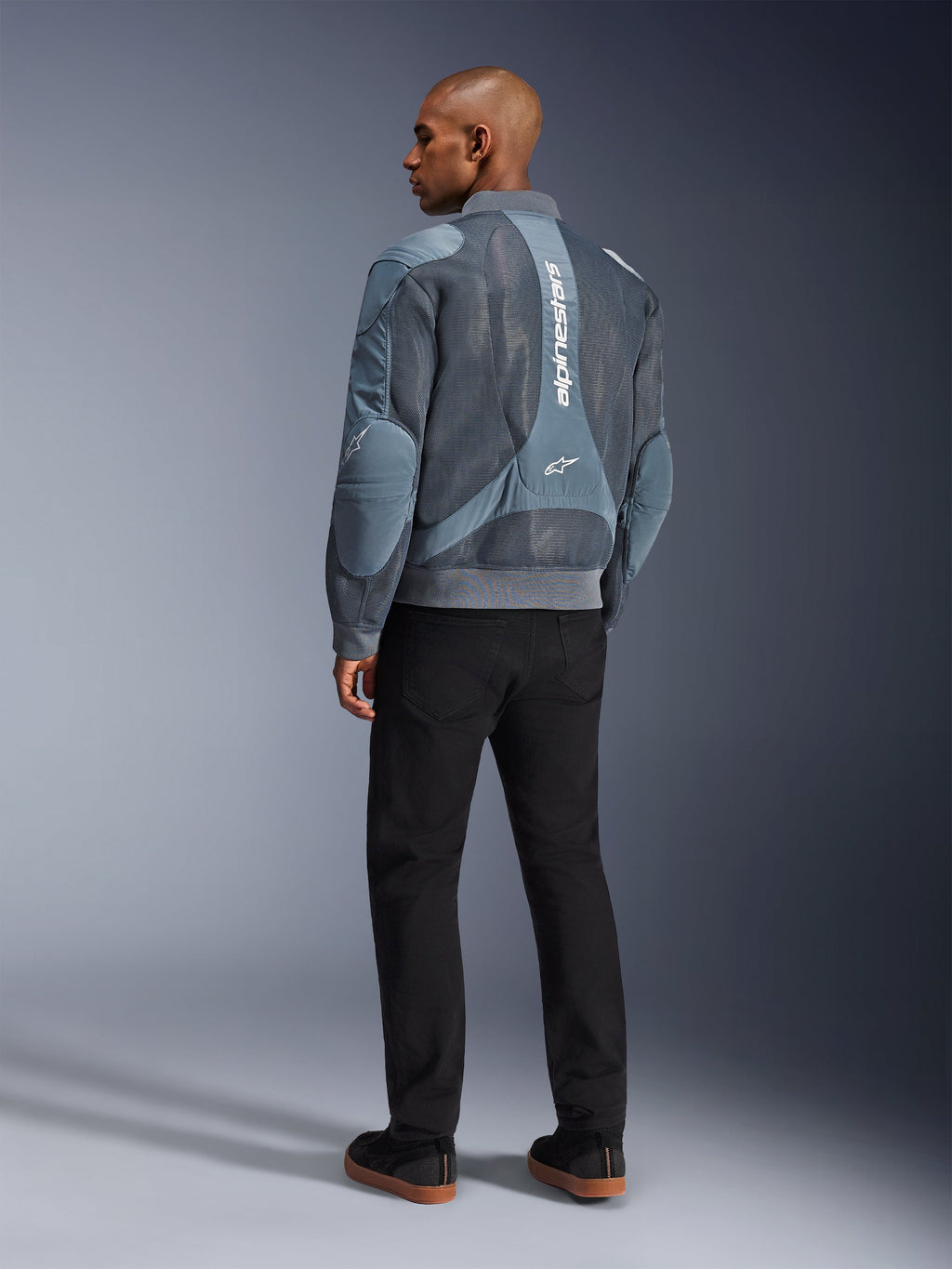 Chaqueta Alpinestars Flight Air, chaqueta de moto Storm Gray, vista posterior, con paneles de ventilación de malla 3D y marca Alpinestars vertical en blanco, combinada con pantalones negros y zapatillas negras, estilo urbano para desplazamientos diarios
