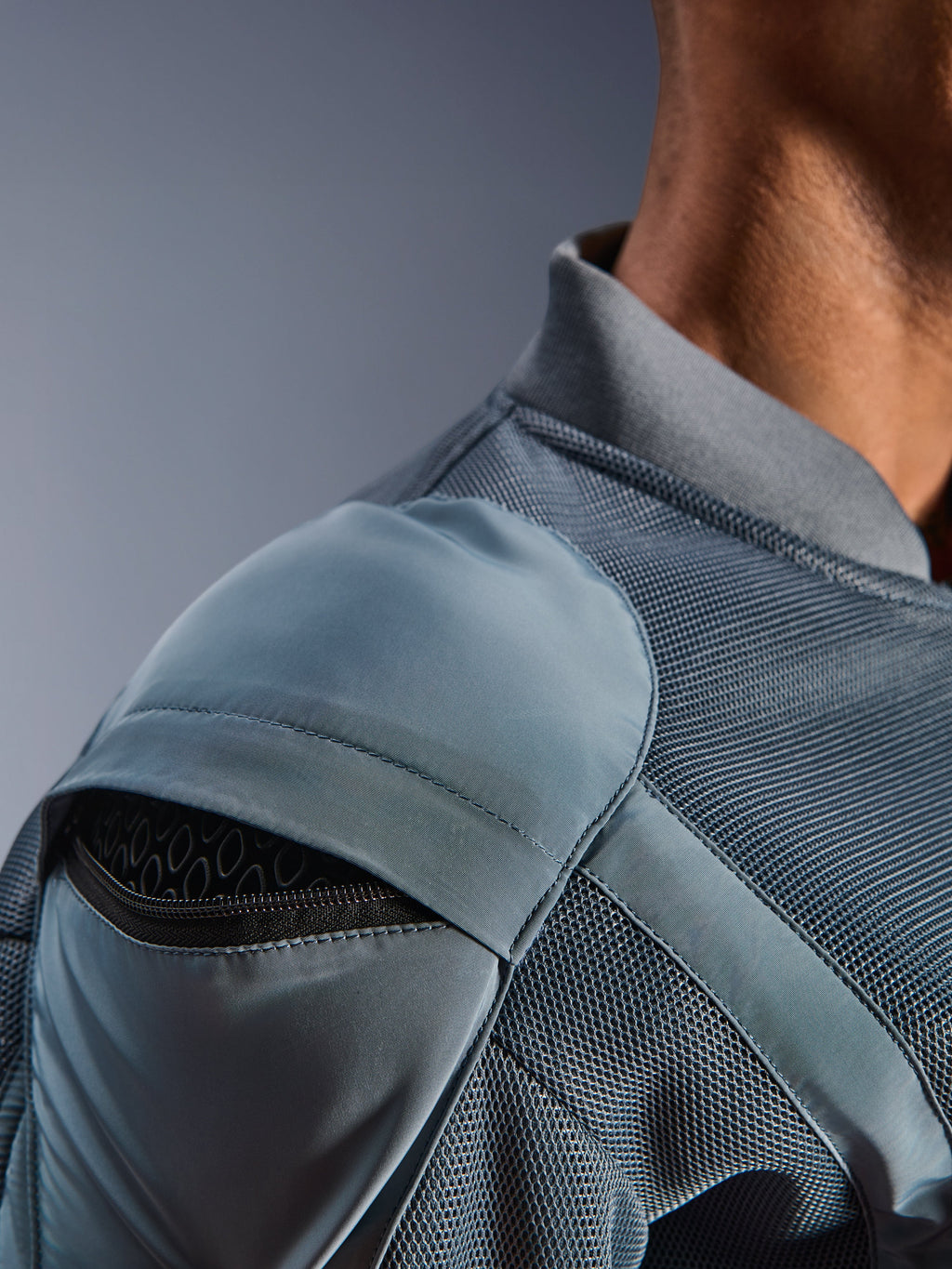 Primer plano de la chaqueta Alpinestars Flight Air en color Storm Gray, que destaca el bolsillo exterior para el protector de hombro con la armadura de panal visible, los paneles de ventilación de malla 3D y el cuello acanalado para la conducción urbana técnica en moto