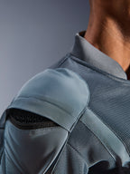 Primer plano de la chaqueta Alpinestars Flight Air en color Storm Gray, que destaca el bolsillo exterior para el protector de hombro con la armadura de panal visible, los paneles de ventilación de malla 3D y el cuello acanalado para la conducción urbana técnica en moto