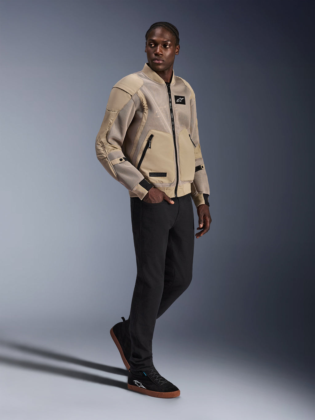 Chaqueta Alpinestars Flight Air, chaqueta urbana para motocicleta, color Aluminum, usada por un modelo con pantalones negros y zapatillas negras, con paneles de ventilación de malla 3D y un diseño estilo bomber, estilo urbano moderno para conducción en ciudad.