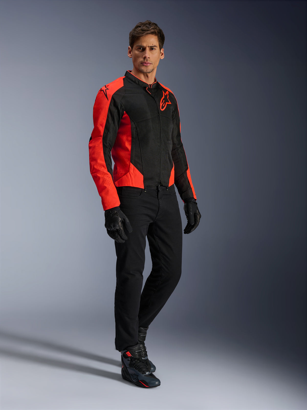 Chaqueta Alpinestars Viper Air V4, chaqueta de moto, rojo fluo y negro, usada por un modelo con vaqueros de moto negros, guantes negros y calzado de moto, diseño de malla textil con llamativos paneles rojos y logo de estrella, equipamiento deportivo para carretera