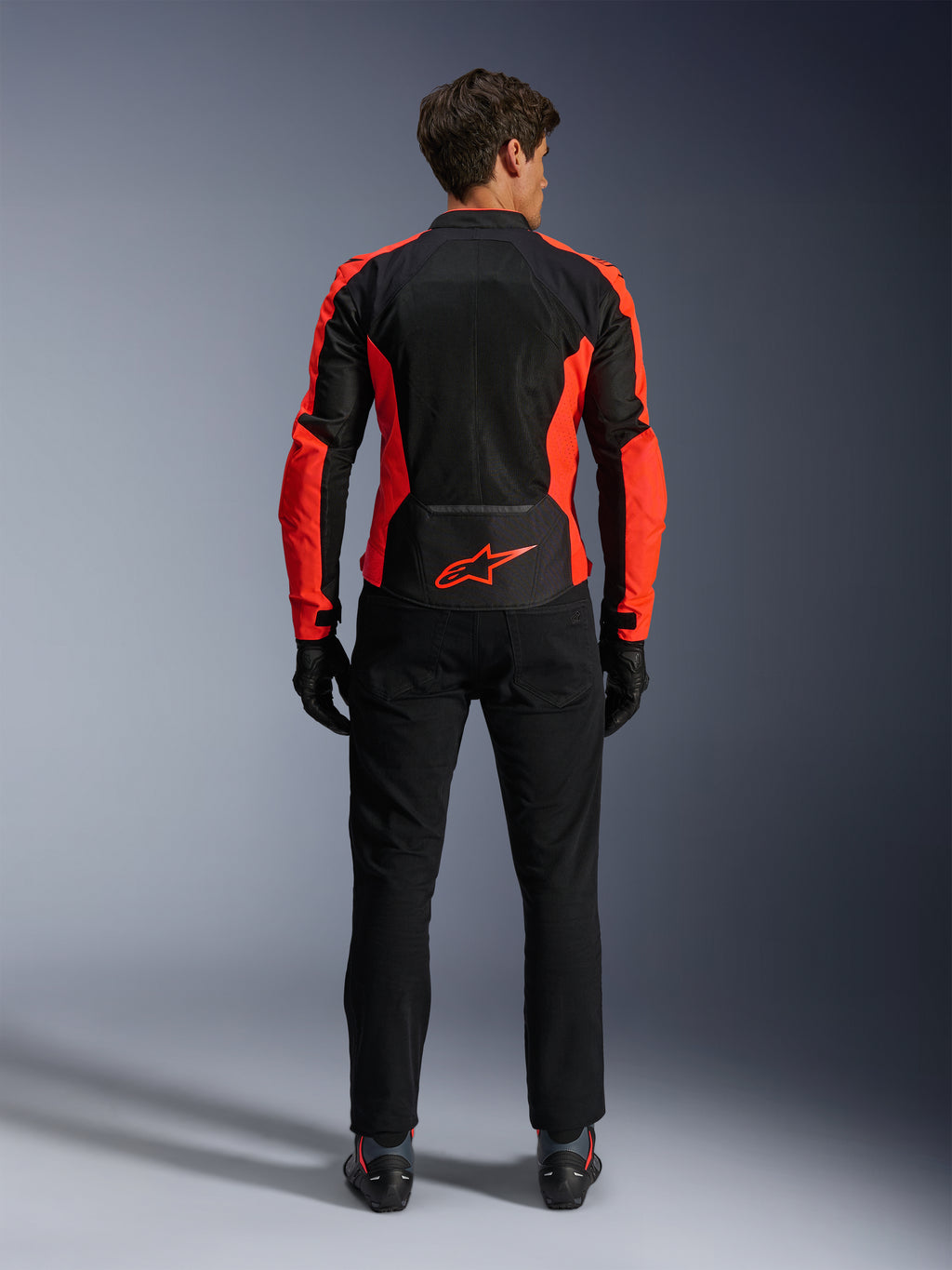 Alpinestars Viper Air V4 Jacket, Red Fluo and Black, back view showing large tech mesh panels and bright red fluorescent side accents, red Alpinestars logo on the lower back, worn with black riding pants and gloves.