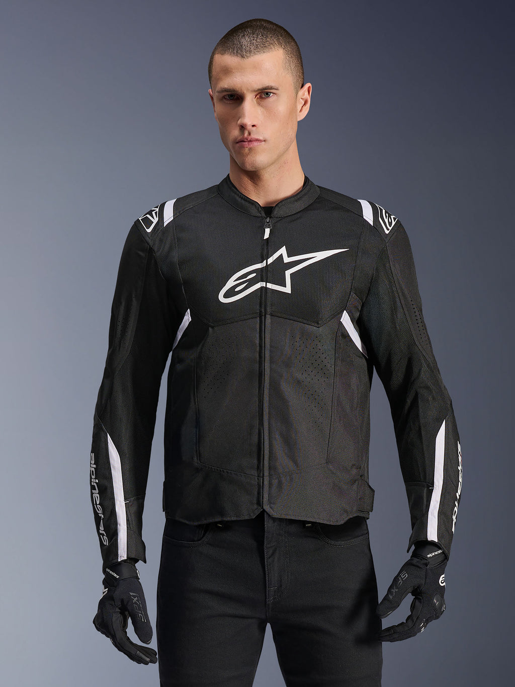 Chaqueta Alpinestars T-SPS Air V2, chaqueta de moto textil para hombre, negra con detalles en blanco, gran logo blanco en el pecho, diseño de malla perforada para ventilación, usada con pantalones y guantes negros