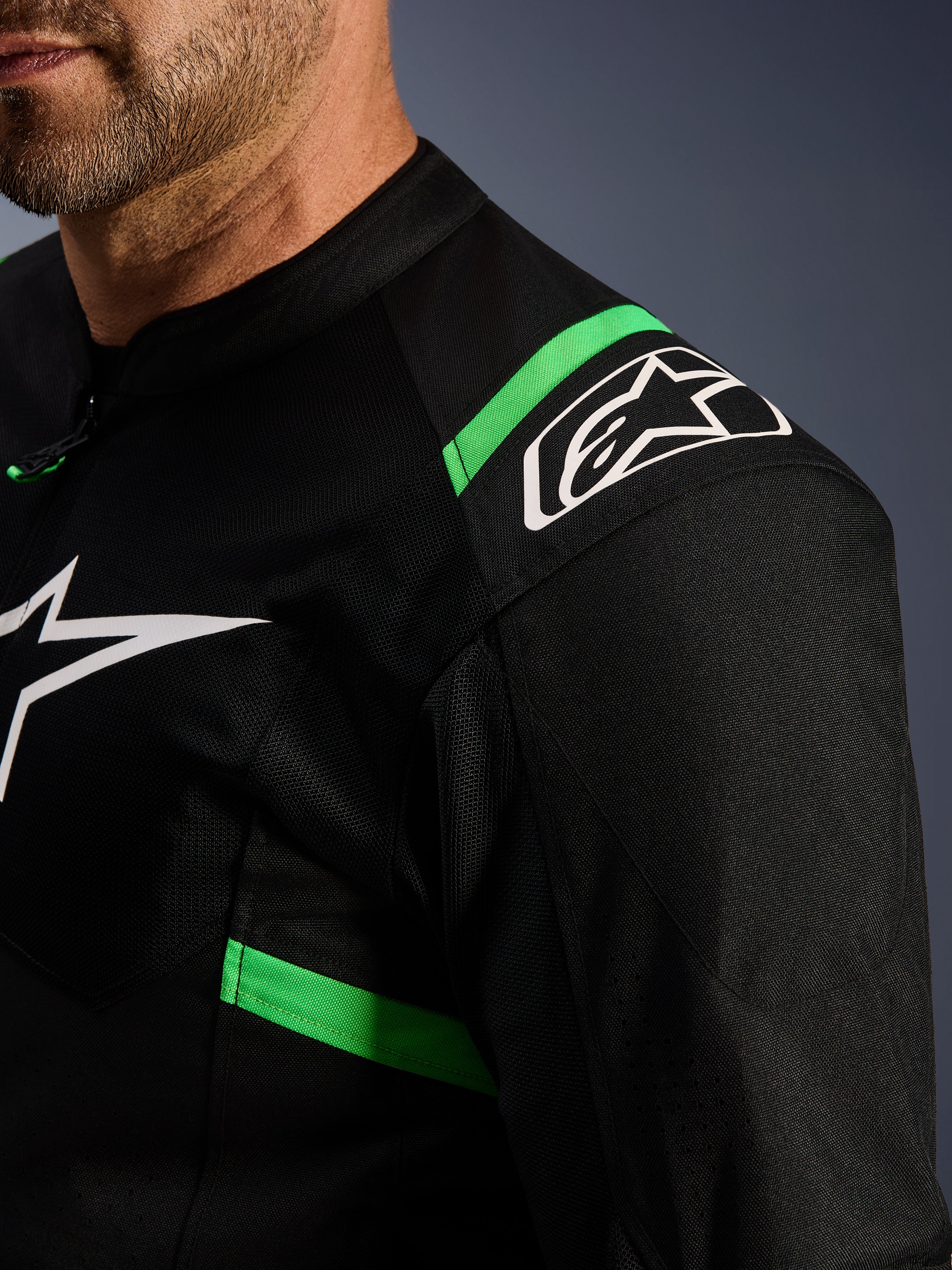 Chaqueta Alpinestars T-SPS Air V2, negra y verde flúor, primer plano del hombro y el pecho, logotipo de la estrella blanca de Alpinestars, tejido de malla técnica para el flujo de aire, chaqueta deportiva para motociclismo