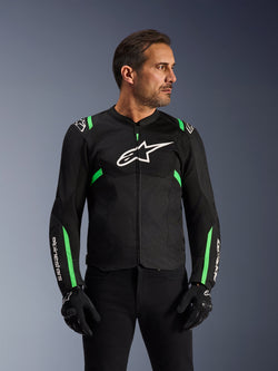 Chaqueta Alpinestars T-SPS Air V2, chaqueta de moto, negro y verde flúor, usada por un modelo con guantes y pantalones de conducción negros, con el logo blanco de Alpinestars en el pecho y detalles en verde neón en hombros y mangas, paneles de malla técnica para ventilación, diseño de corte deportivo para conducción urbana