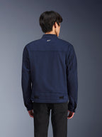 Chaqueta Alpinestars Bruiser, chaqueta de moto textil en azul oscuro, vista posterior en modelo, diseño inspirado en la ropa de trabajo con un pequeño logo blanco de Astars en el cuello, pestañas de ajuste en la cintura, ropa de conducción urbana contemporánea.