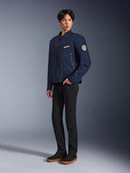 Chaqueta Alpinestars Bruiser en azul oscuro, chaqueta de moto urbana textil con diseño inspirado en la ropa de trabajo, con bolsillos con cremallera en el pecho y parche Oscar en la manga, usada con pantalones negros y zapatillas casuales.