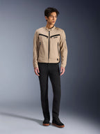Chaqueta Alpinestars Bruiser, chaqueta urbana de motociclismo en color Aluminum, combinada con pantalones negros y zapatillas negras, con bolsillos negros con cremallera y cuello con botón a presión, diseño contemporáneo inspirado en la ropa de trabajo para conducción urbana