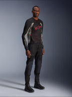 Chaqueta Alpinestars Troop-Air, chaqueta de malla técnica para motocicleta en negro, gris ceniza y rojo brillante, usada por un modelo con pantalones y botas negros a juego, con un logotipo de Alpinestars rojo en el pecho, equipamiento de conducción urbano contemporáneo.