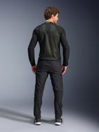 Chaqueta Alpinestars Troop-Air, Negro Amarillo Flúor, vista trasera en un modelo, con un gran panel posterior de malla técnica 2D para ventilación, chaqueta técnica de motociclismo usada con pantalones y botas de conducción negros, estilo de moto urbano