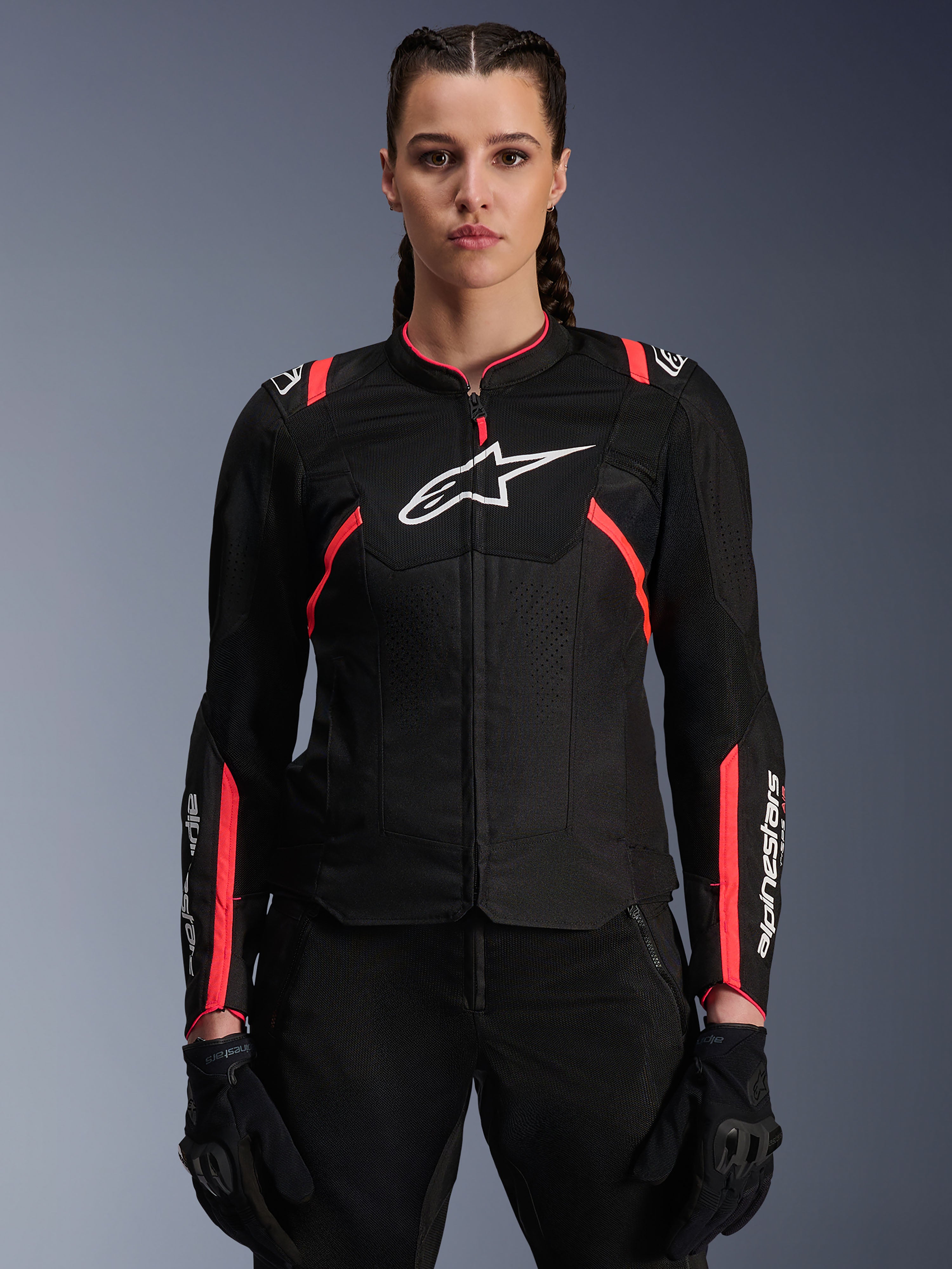 Alpinestars Stella T-SPS Air V2 Jacket, chaqueta de moto para mujer, negra y rosa diva, construcción textil ventilada con logotipo blanco, detalles rosas de inspiración deportiva en hombros y mangas, usada por una modelo