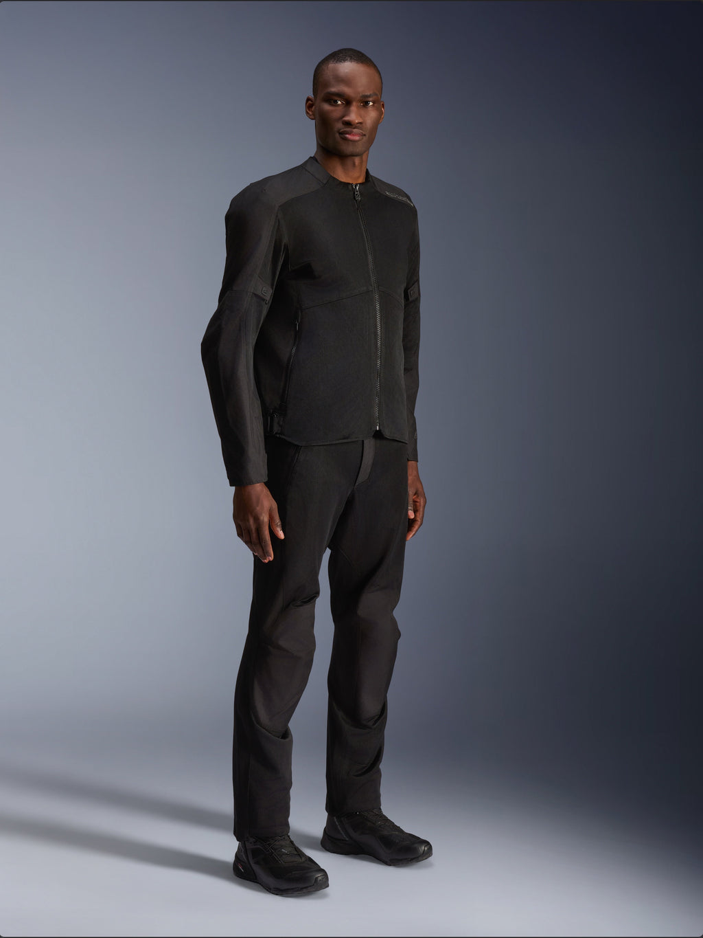 Chaqueta Alpinestars C-1 Air, negra, lucida por un modelo con pantalones de moto y calzado negros a juego, con amplios paneles de malla técnica para el flujo de aire, estética urbana limpia y ajuste estilizado.