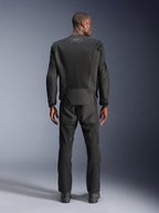 Vista posterior de un hombre con la chaqueta Alpinestars C-1 Air en color negro, chaqueta de moto urbana con paneles de malla técnica, pantalones textiles y botas negras a juego, estética limpia con logotipo reflectante en la parte superior de la espalda.