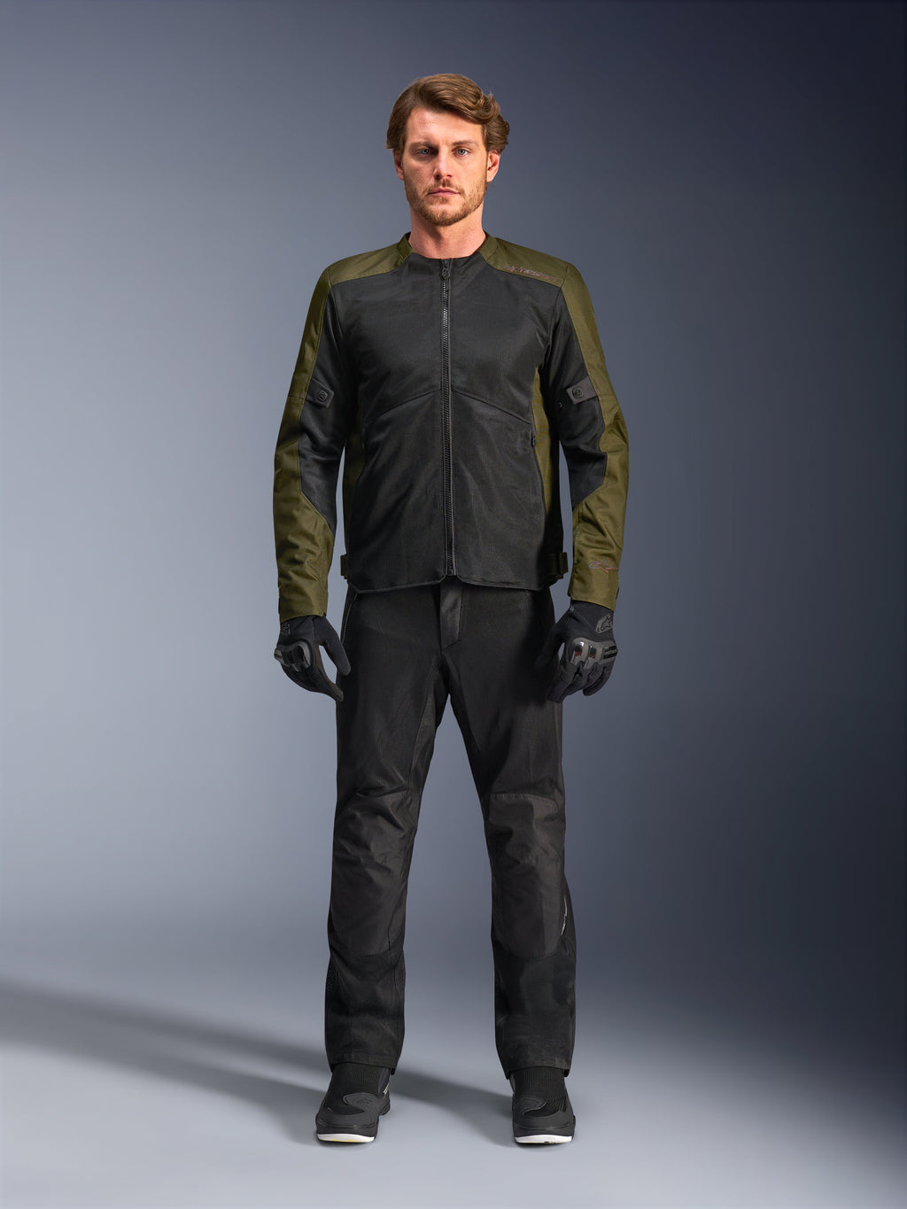 Chaqueta Alpinestars C-1 Air, caqui y negro, modelo masculino con pantalones de moto y guantes negros, diseño textil ligero con paneles de malla técnica, equipamiento de conducción urbano contemporáneo
