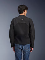 Chaqueta Alpinestars Provoke, chaqueta de moto urbana, negra, vista trasera que muestra el logo blanco de Astars y paneles técnicos de ripstop, combinada con pantalones vaqueros azules, diseño contemporáneo para desplazamientos urbanos
