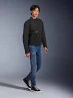 Chaqueta Alpinestars Provoke, chaqueta de moto urbana, negra, vestida por un modelo masculino con vaqueros azules y zapatillas negras, diseño textil técnico con un pequeño logotipo de Alpinestars, foto de estilo de vida de cuerpo completo para conducción urbana contemporánea.