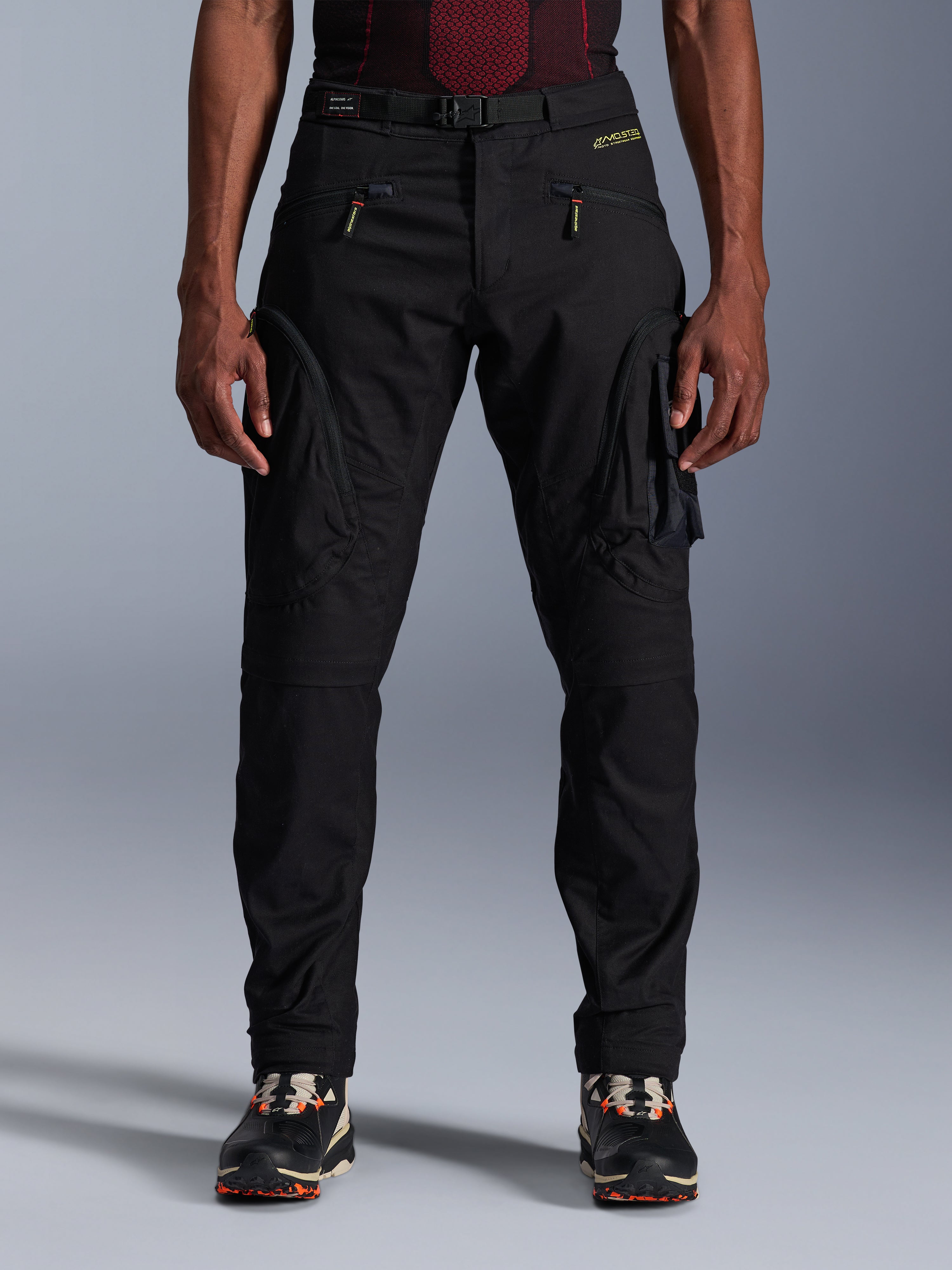 Alpinestars Acteon Pants, pantalones de moto urbanos negros, corte regular ajustado con bolsillos cargo laterales y cremalleras de espiral inversa, cinturón integrado y detalles de marca en amarillo, equipamiento textil de protección para motorista