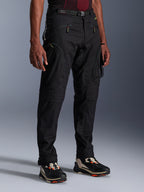 Pantalones Alpinestars Acteon, pantalones de moto negros usados por un modelo, con una silueta moderna y ajustada, bolsillos cargo con cremallera, cinturón ajustable y zapatillas técnicas, equipamiento para conducción urbana