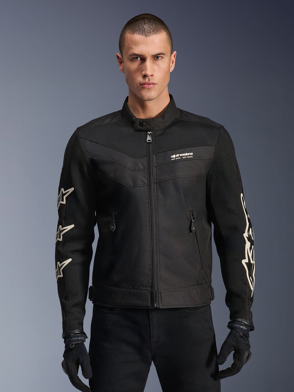 Alpinestars T-Dyno Air Jacket, chaqueta de moto textil negra, con gráficos de estrellas blancas en las mangas y logotipo en el pecho, paneles de malla para ventilación, ajuste de motociclista de inspiración vintage, usada con guantes y pantalones negros