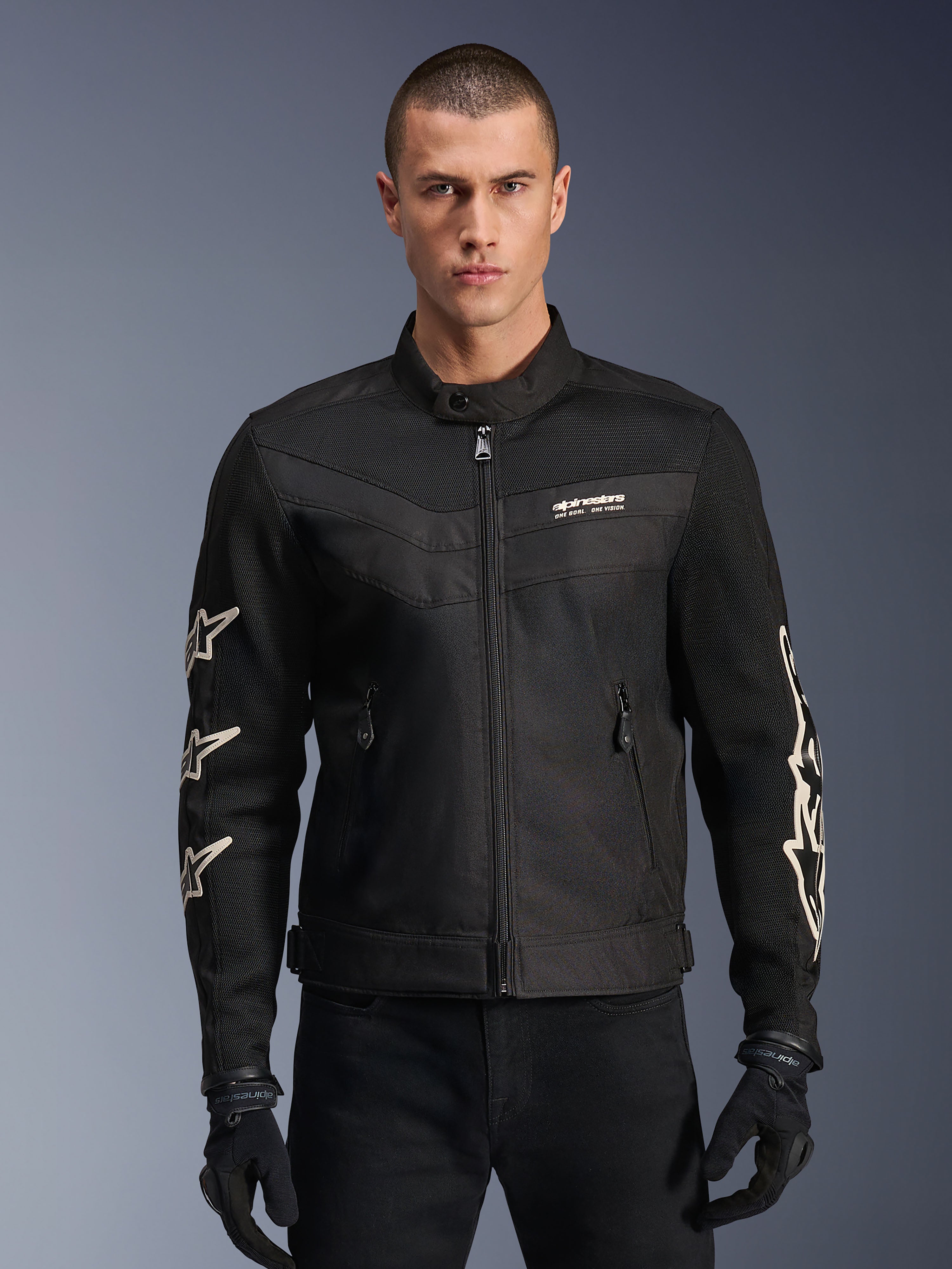 Alpinestars T-Dyno Air Jacket, chaqueta de moto textil negra, con gráficos de estrellas blancas en las mangas y logotipo en el pecho, paneles de malla para ventilación, ajuste de motociclista de inspiración vintage, usada con guantes y pantalones negros