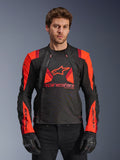 Alpinestars T-Stunt Air Jacket, chaqueta de moto textil, negro, rojo fluo y rojo oscuro, con un gran logo de estrella y paneles de malla para el flujo de aire, usada por un modelo con guantes negros