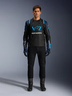 Chaqueta Alpinestars T-Stunt Air, chaqueta de moto, negra con detalles en azul oscuro y azul brillante, con un gran logotipo blanco en el pecho, construcción de malla de corte deportivo para el flujo de aire, combinada con pantalones y botas de motociclista negros para una estética elegante de conducción en carretera.