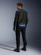 Chaqueta Alpinestars T-Stunt Air, chaqueta de moto, negra con detalles en azul oscuro y azul Blithe, vista posterior que muestra los paneles de malla modulares y el logotipo en la parte baja de la espalda, usada por un modelo con pantalones de moto y botas negros.