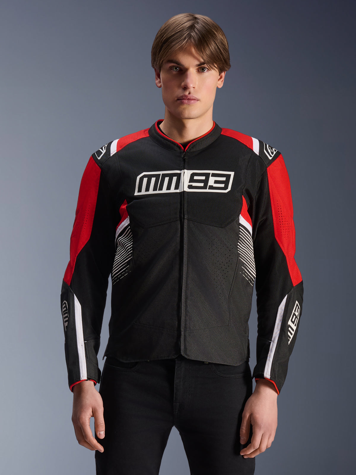 MM93 T-SPS Air V2 Jacket, Textile Motorcycle Jacket in Black Bright Red and White, featuring Marc Márquez signature MM93 branding on chest and sleeves, mesh paneling for ventilation, sports cut design, worn by model with black pants
