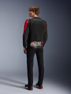 Modelo de espaldas con la chaqueta Alpinestars MM93 T-SPS Air V2, negra con detalles en rojo brillante y blanco, con el texto 'MARC MARQUEZ' y un logotipo '93' grande en la parte trasera, construcción de malla textil para ventilación, combinada con pantalones negros y calzado de moto a juego en negro y rojo