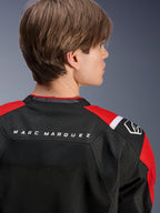 Chaqueta Alpinestars MM93 T-SPS Air V2, vista posterior de la parte superior de la espalda y los hombros, negro con detalles en rojo brillante y blanco, texto 'MARC MARQUEZ' en el canesú, con paneles de malla técnica y logotipo en el hombro, ropa de moto deportiva urbana