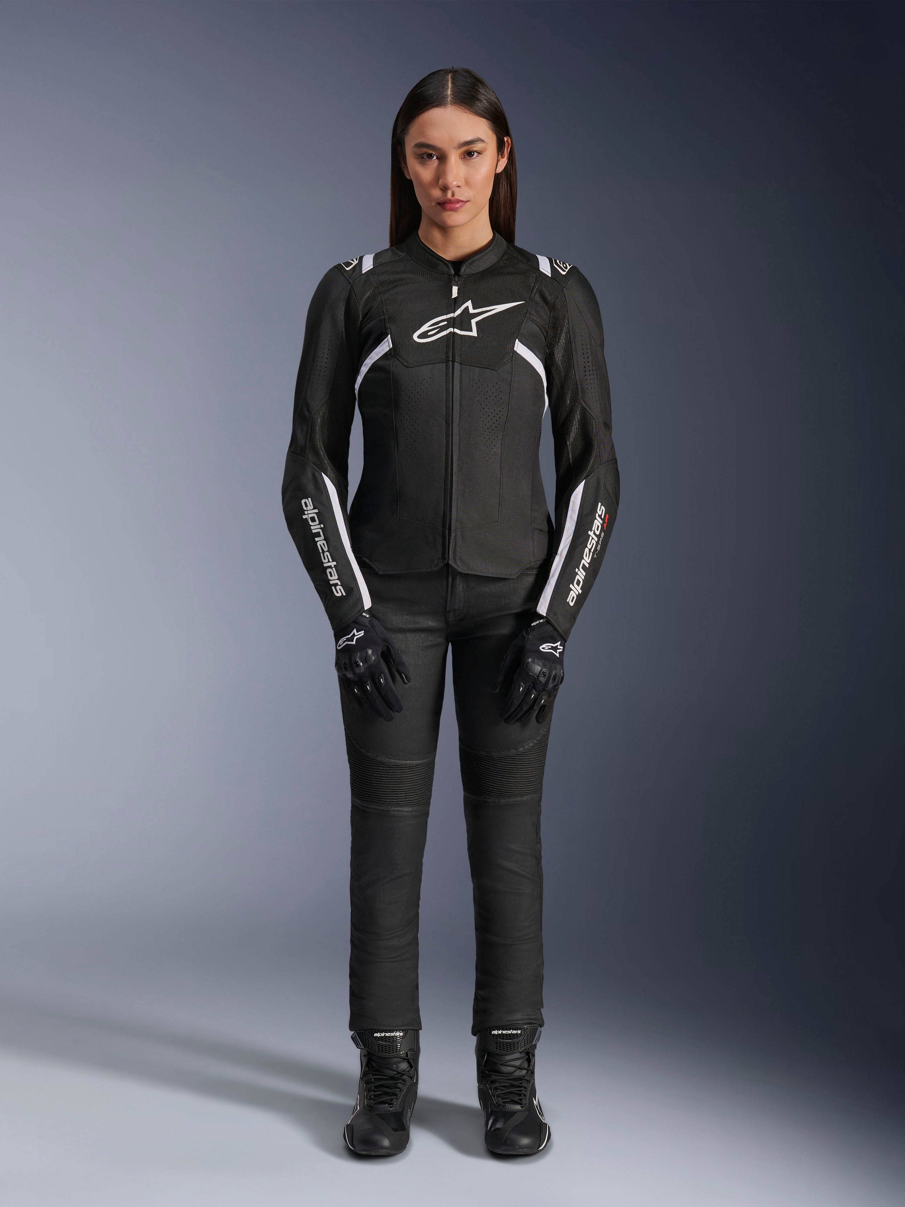 Chaqueta Alpinestars Stella T-Sps Air V2, chaqueta de moto para mujer, negra y blanca, con paneles de malla y detalles blancos, usada con pantalones, guantes y botas negros, ajuste deportivo para conducción urbana