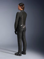 Chaqueta Alpinestars Stella T-Sps Air V2, negra y blanca, vista trasera que muestra paneles de malla y el logotipo en la parte inferior de la espalda, combinada con pantalones de conducción negros y calzado para moto, equipamiento textil deportivo de carretera para mujer
