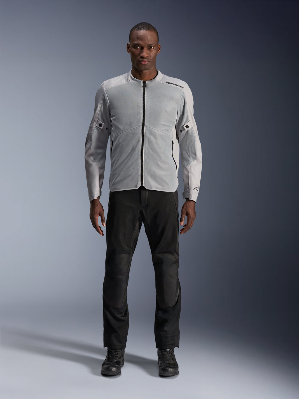 Alpinestars C-1 Air Jacket en Silver, chaqueta de moto textil urbana para hombre con paneles de malla ventilada, usada por un modelo con pantalones de moto negros y botas negras, estilo contemporáneo para trayectos urbanos