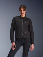 Chaqueta Alpinestars Stella Grace para mujer, chaqueta de moto urbana, negra, vista frontal, con múltiples bolsillos con cremallera y cuello con botón a presión, combinada con vaqueros negros, equipamiento de protección para mujer de estilo urbano moderno