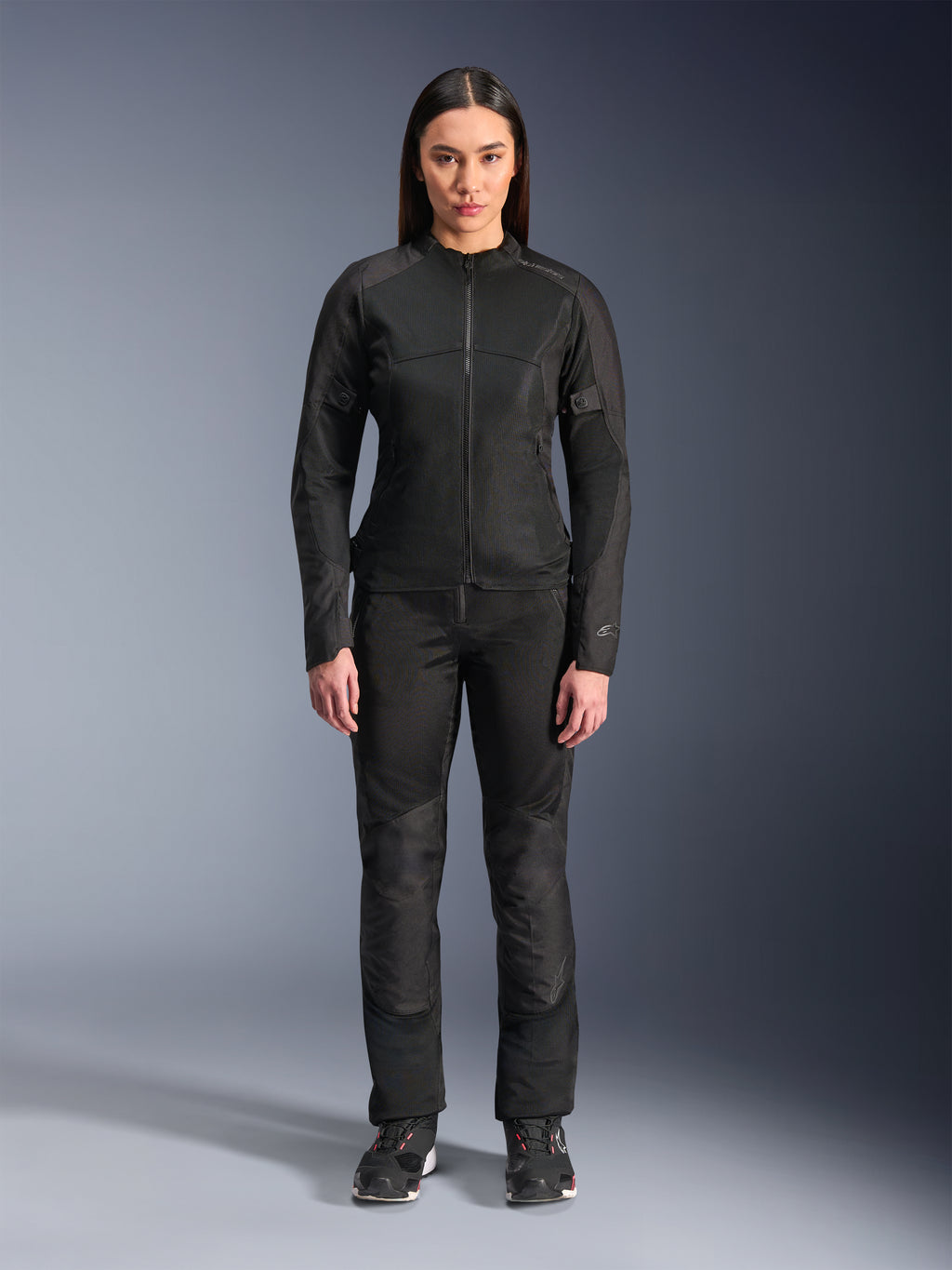 Mujer vistiendo la chaqueta Alpinestars Stella C-1 Air en negro, combinada con pantalones textiles de moto y calzado de conducción a juego, con un diseño urbano elegante y amplios paneles de malla para el flujo de aire.
