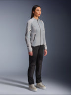Mujer vistiendo la chaqueta Alpinestars Stella C-1 Air en color plateado, chaqueta de moto de tejido ligero y malla, combinada con pantalones de conducción negros y zapatillas casuales, estética de conducción urbana limpia.
