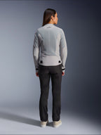 Mujer con la chaqueta Alpinestars Stella C-1 Air en color plateado, vista trasera, con grandes paneles de malla técnica para ventilación y un logotipo de estrella reflectante, combinada con pantalones de motociclista negros y zapatillas blancas, equipamiento de moto urbano contemporáneo