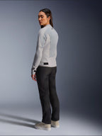 Mujer con la chaqueta Alpinestars Stella C-1 Air en plateado, vista trasera y lateral que muestra los paneles de malla técnica y el logotipo reflectante en el hombro, combinada con pantalones de moto negros y zapatillas beige, estética de conducción urbana contemporánea