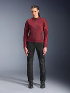 Chaqueta Alpinestars Stella C-1 Air para mujer, chaqueta de moto textil en color burdeos, con paneles de malla para ventilación y bolsillos con cremallera, lucida por una modelo con pantalones de moto y botas negros, equipamiento de conducción urbana contemporánea para mujer