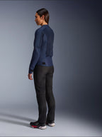 Mujer con la chaqueta Alpinestars Stella C-1 Air en azul, vista trasera de tres cuartos, que muestra los paneles de malla en la espalda y las pestañas de ajuste en la cintura, combinada con pantalones de motociclismo negros y zapatillas negras, ropa de moto urbana